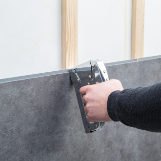 Dumawall wandpaneel dat met een nietpistool op een houten regelwerk wordt bevestigd.